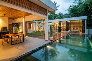 a house with a swimming pool and a dining room at Rouge - Loft Emylia in Ubud