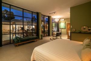 a bedroom with a bed and a couch and windows at Rouge - Loft Emylia in Ubud +27 photos