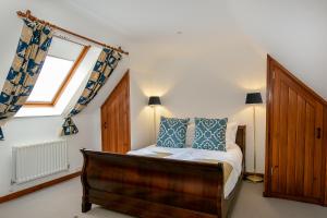 a bedroom with a bed with blue pillows and a window at Cotswolds Barn Near Soho Farmhouse & Daylesford in Chipping Norton