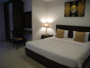 a bedroom with a bed and a desk with a lamp at Green House Phuket in Ban Pa Khlok