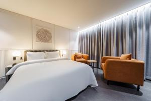 a bedroom with a large white bed and a chair at Brown Dot Hotel Geumchon in Paju