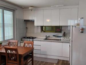 a kitchen with white cabinets and a table and a refrigerator at Gujeolcho Guesthouse in Gyeongju +18 photos