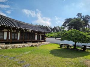 Un edificio con un banco y un árbol en el césped. en Dobong Seodang, en Gyeongju