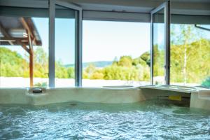 a jacuzzi tub in a house with windows at Domek przy Modrzewiach in Bachórzec