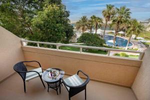 a balcony with a table and chairs and a pool at Metropolitan Al Mafraq Hotel in Abu Dhabi