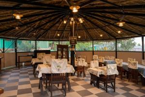 a restaurant with white tables and chairs and a ceiling at Dev Bhoomi Farms & Cottages in Dharamshala