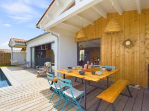 a wooden deck with a wooden table and chairs at Villa d'architecte avec Piscine chauffée et jardin in Rivedoux-Plage
