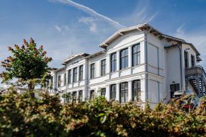Un edificio blanco con árboles delante. en Strandvilla Ostpreussen - Dependance Strandhus, en Ahlbeck