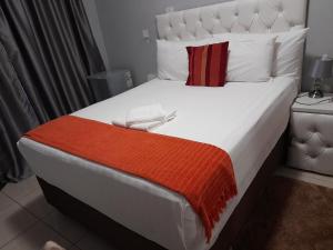 una camera da letto con un grande letto bianco con una coperta arancione di Rest & Digest a Serowe Altre 18 foto