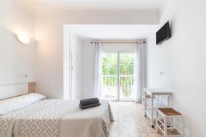 Una habitación blanca con una cama y una ventana en Hostal Moya, en Roquetas de Mar
