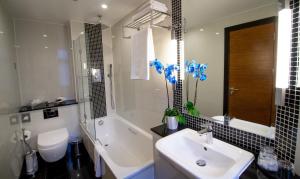 a bathroom with a sink and a tub and a toilet at Wellington Hotel by Blue Orchid in London