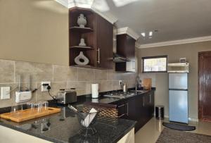 a kitchen with a black counter top with a refrigerator at Hornbill Self Catering Cottages Muldersdrift in Krugersdorp