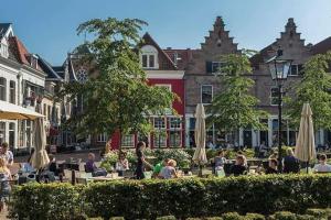 a group of people sitting at tables with umbrellas at Forest Cottage Hattem in Hattemerbroek