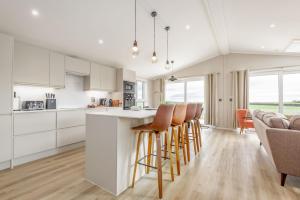 a kitchen with white cabinets and a bar with chairs at Eden View Estate - Eden Lodge in St. Andrews