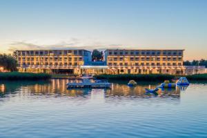 un edificio en un río con barcos en el agua en Sirius Hotel****Superior, en Keszthely