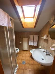 łazienka z umywalką, toaletą i oknem dachowym w obiekcie Hotel Eira w mieście Bormio