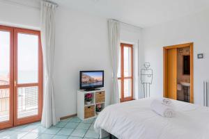 a white bedroom with a bed and a television at Casa Elan Salerno in Salerno