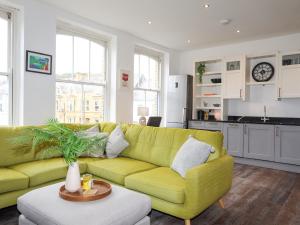 a living room with a yellow couch and a kitchen at Harbourside Apartment in Pwllheli +24 photos