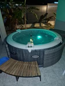 a hot tub with a table and a bench at charmante Villa avec Jacuzzi, jardin et BBQ in Le Vauclin