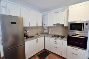 a kitchen with white cabinets and a stainless steel refrigerator at FLH - Apartament Kathy Sibiu in Turnişor
