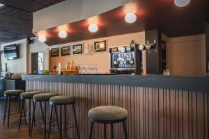 a bar with four stools at a bar at Hôtel du Golf Saint Lazare in Limoges