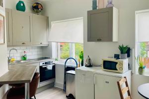a kitchen with white cabinets and a table with a microwave at Luxury House - 2 x Double Beds w Ensuites in Spon End +8 photos