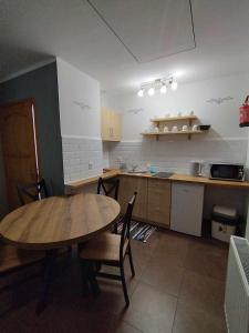 a kitchen with a wooden table and chairs in it at Domek HAWRAŃ in Jurgów