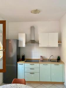 a kitchen with white cabinets and a stainless steel refrigerator at Casa Estia in Santa Teresa Gallura