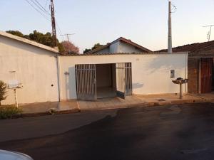 a white building with a garage on the side of a street at Casa simples confortável c Ar-cond p 6 Pessoas in Araçatuba