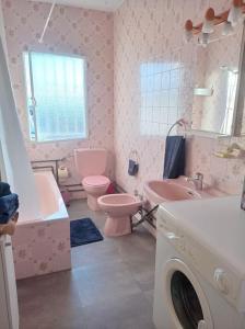 a pink bathroom with a sink toilet and a washing machine at Casa de la Ermita in Alhaurín de la Torre