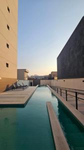a pool of green water next to two buildings at Studio Pôr do Sol - Garagem - Piscina - Anhembi in São Paulo