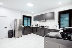 eine Küche mit einem Edelstahlkühlschrank und schwarzen Schränken in der Unterkunft Sea'cret Stay Villa Pattaya พัทยา พูลวิลล่าพัทยา ใกล้ทะเล in Na Jomtien