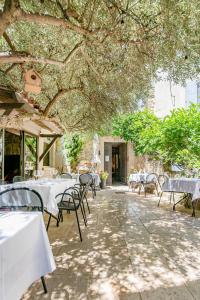 a restaurant with tables and chairs under a tree at La Prévôté - Hôtel Particulier & Restaurant in LʼIsle-sur-la-Sorgue