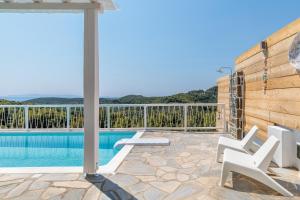 a patio with a swimming pool and white chairs at Villa Zoe in Panormos Skopelos