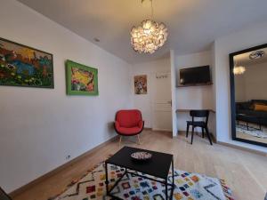 a living room with a red chair and a table at Studio climatisé avec jardin - proche Paris in Saint-Maur-des-Fossés