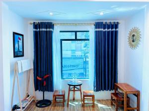 a room with blue curtains and a table and a window at TÍ LẦU HOMESTAY Tours & Motorbike Rental in Ha Giang