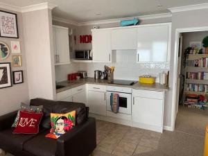 eine Küche mit weißen Schränken und einem Sofa im Wohnzimmer in der Unterkunft Jurassic Coast Holiday Home in Charmouth