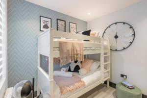 Pokój z łóżkami piętrowymi i zegarem na ścianie w obiekcie Unwind in Style 2BR with Cozy Backyard for Groups w Londynie