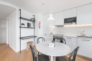 eine Küche und ein Esszimmer mit einem weißen Tisch und Stühlen in der Unterkunft GuestReady - Riverview Douro Balcony in Vila Nova de Gaia