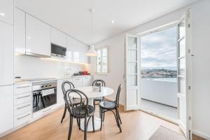 eine Küche mit weißen Schränken und einem Tisch mit Stühlen in der Unterkunft GuestReady - Riverview Douro Balcony in Vila Nova de Gaia
