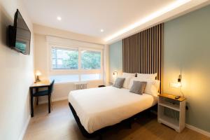 马德里I'M Room Suites Nuevos Ministerios - Bernabeu 'Digital Access'的一间卧室，配有一张床、一张书桌和一扇窗户