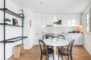 eine weiße Küche mit einem weißen Tisch und Stühlen in der Unterkunft GuestReady - Riverview Douro Balcony in Vila Nova de Gaia + 23 Fotos