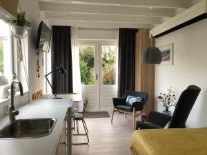 a kitchen and living room with a sink and chairs at DeZwarteRuiter in Callantsoog