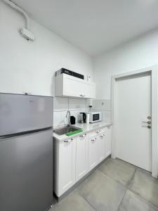 a kitchen with white cabinets and a refrigerator at ZAN studios by the sea in Netanya