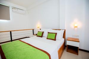 a bedroom with a large white bed with green accents at Seaview Terrace in Weligama