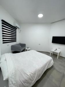 a white bedroom with a bed and a flat screen tv at ZAN studios by the sea in Netanya
