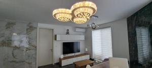 a living room with a television and a chandelier at PrimRose Lux Loft in Xewkija
