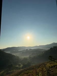 a view of a valley with the sun in the sky at Pousada nas Montanhas Recanto Querubins in Paty do Alferes