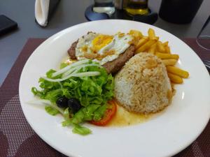 a white plate of food with eggs and rice and french fries at Lazúli Flats in Luanda