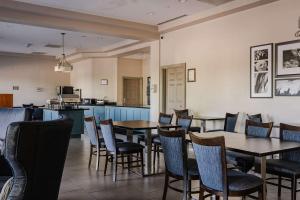 a restaurant with tables and chairs and a kitchen at Country Inn & Suites by Radisson, BWI Airport Baltimore , MD in Linthicum Heights